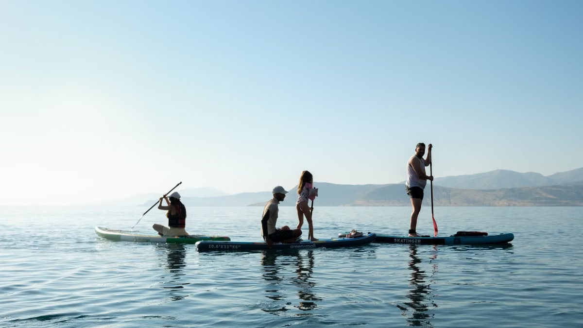 A group of people paddleboarding on a calm lake under clear blue skies.